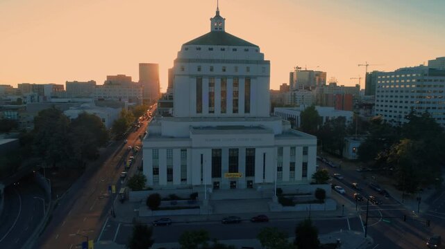 Alameda County Courthouse at sunrise. The sun shines down the street, creating a warm glow over the city skyline. Oakland, California, USA. 10 June 2025.