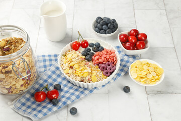 Healthy oatmeal breakfast bowl with fresh berries, granola and milk on white wooden background
