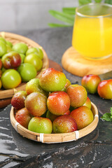 Fresh Organic Plums in Bamboo Basket with Orange Juice on Dark Marble Background