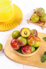 Fresh Colorful Plums with Cubed Flesh in Wooden Bowl on Bamboo Cutting Board