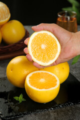 Fresh Orange Half in Hand with Citrus Fruits on Slate Board - Healthy Eating and Vitamin C Concept