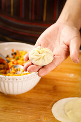 Hand Holding Fresh Chinese Dumpling Xiao Long Bao with Flour and Filling for Traditional Asian Cooking