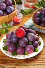 Freshly Picked Red Plums with Shiny Skin on Rustic Wooden Table