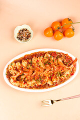 Garlic Shrimp in Spicy Tomato Sauce with Cherry Tomatoes and Herbs on Peach Background