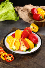 Freshly picked colorful bell peppers from Shandong province on white plate with lettuce and wooden bowl background