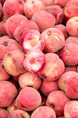 Freshly Stacked Ripe Peaches at Market Display with Cut Peach Showing Red Flesh