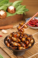 Fried Silkworm Pupae in Bowl with Chopsticks - Traditional Asian Insect Food on Bamboo Mat
