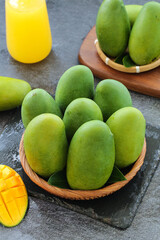 Fresh Green Mangoes in Wooden Bowls with Tropical Fruit Display on Dark Slate Background