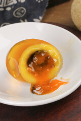 Golden egg yolk flowing in white bowl - fresh cracked egg with loose runny texture for cooking and breakfast preparation