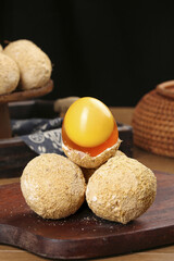 Raw chicken egg with golden yolk in breadcrumb coating on wooden cutting board for cooking preparation