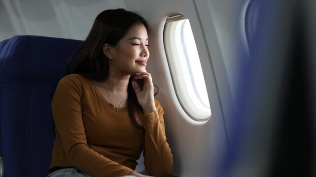 Young woman looking out airplane window during flight. Pensive passenger sitting near airplane window, gazing at expansive sky while contemplating upcoming journey.