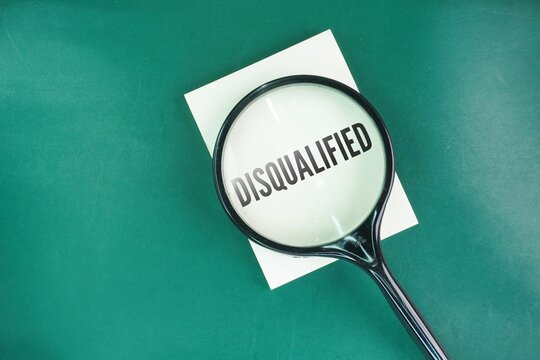 Magnifying glass with the word disqualified. concept of disqualification. declared ineligible for an office, activity, or competition because of an offence or infringement.