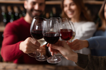 Friends clinking glasses of red and white wine in a warm, cozy setting, celebrating and enjoying a joyful moment together