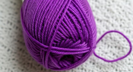 Close-up of vibrant purple yarn ball sitting atop a textured white knitted background, ideal for crafting projects.