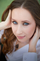 Naklejka premium Portrait of a woman with striking blue eyes and long brown hair in a relaxed pose outdoors