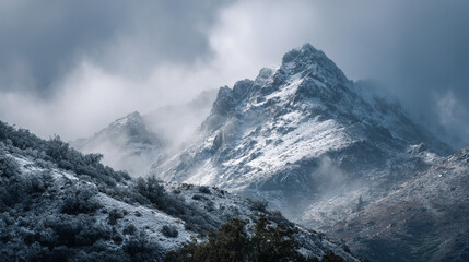 A snowy mountain range shrouded in mist and low clouds on a cold and overcast winter day