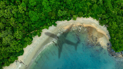 Aerial view of shadow passenger plane silhouette and sandy beach blue sea with waves at sea beach summer vacation sea travel concept	
