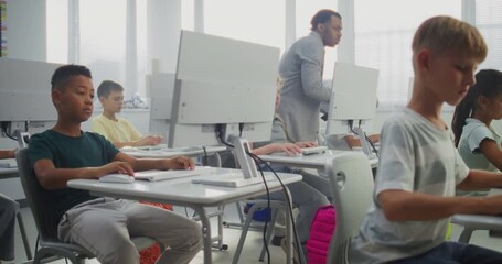 Primary School Students Working on Computers. Teacher Guiding Diverse Kids in Practicing Digital Skills and Studying Programming in Computer Science Classroom. Interactive STEM Learning. Dolly Shot. - Powered by Adobe