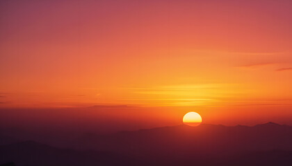 Obraz premium A tranquil scene with the sun setting behind distant mountains, radiating a golden glow.