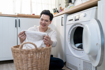 Asian mature man doing laundry in kitchen at home.
