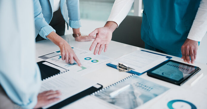 Hands, doctor and team at office meeting with documents, graphs and review for medical research at hospital. People, clinic director and healthcare staff in group with tech, charts and paperwork