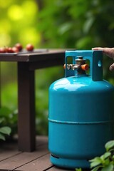 Close-up shot of a propane tank connected to a gas grill, ready for outdoor cooking The blue propane tank is clearly visible against a green, leafy background , gas cylinder, lpg, domestic