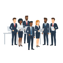 Diverse business team in suits standing together, some holding laptops and documents, in a professional setting.