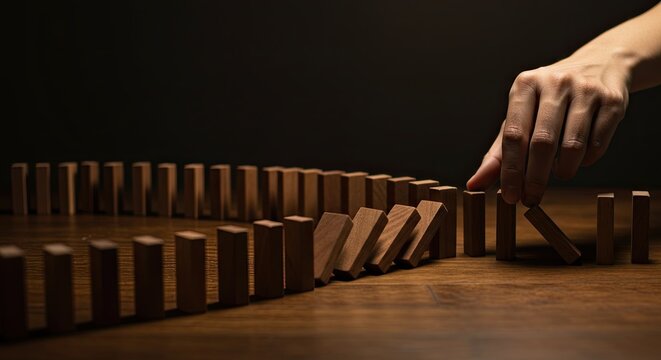 Falling Wooden Dominoes Hand Triggering Brown Domino Effect on Wood