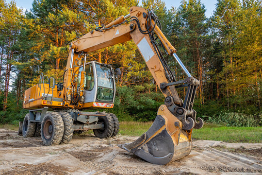 Wheeled excavator resting after earthmoving works - Powered by Adobe