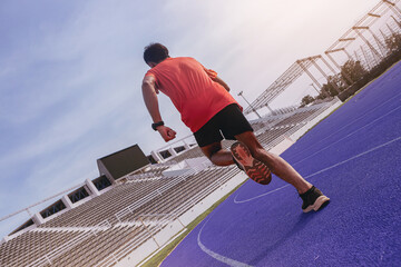 Fit young man running sprinting at the racetrack. Fit runner fitness runner during outdoor workout at racetrack.