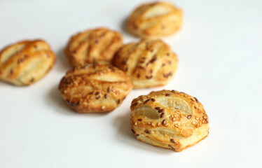 Mini pies with sesame seeds on white background