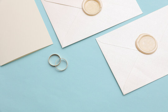 Wedding invitation card, Envelopes with wax seals, gold rings on blue background. Top view. Flat lay