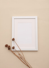 Mockup of white photo frame with dry grass on beige background