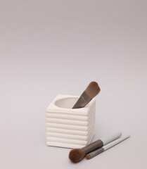 Makeup brushes in concrete cup on grey background. Fashion, beauty concept