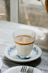 Cup of coffee latte  served on the white plate on a wooden table in coffee shop. 