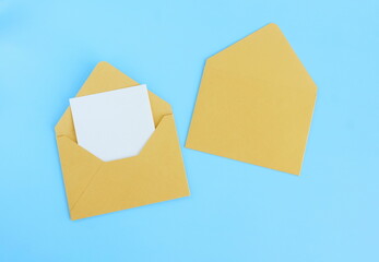 Gold envelope with blank paper card mockup  inside top view on turquoise background . Copy space.Minimalist aesthetic wedding invitation mockup, greeting card, holiday concept.