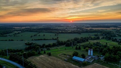 Drone view of farm landscape with silos and fields at sunset