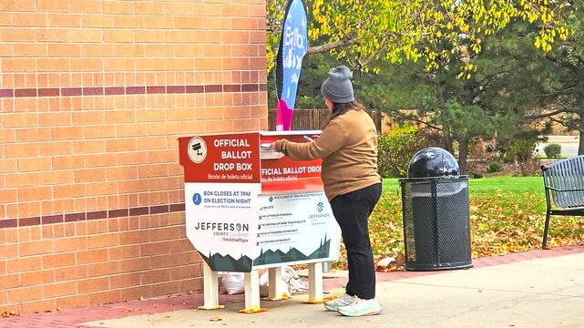 Voting securely is shown as a woman drops her mail-in ballot envelope into an official ballot box, representing civic duty, freedom, trust, equality, inclusivity, safety, the importance of democracy.