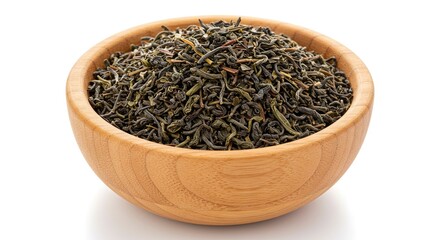 Fototapeta premium A wooden bowl brimming with curled dark green tea leaves sits on a white surface casting a soft shadow