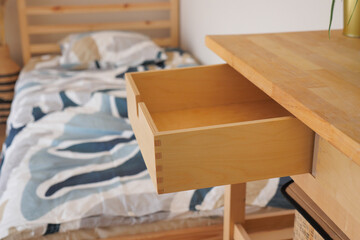 Wooden drawer open beside a bed in a cozy room