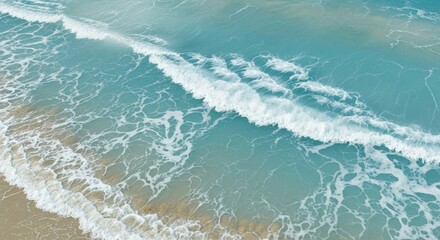 Fototapeta premium Waves crashing on a sandy beach with clear turquoise water.