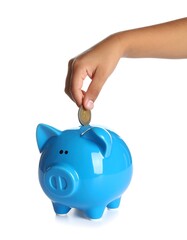 Child's hand placing a coin in a blue piggy bank