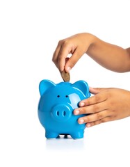 Child's hands putting coin into blue piggy bank