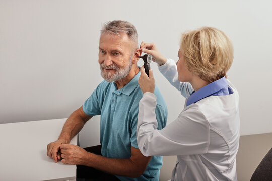 Senior man during ear test with audiologist at audiology. Diagnosis of impairment and hearing testing to senior people, otoscopy - Powered by Adobe