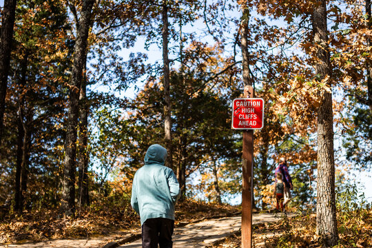 Family hiking past sign warning high cliffs ahead