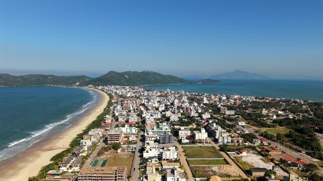 Panoramic drone fly over the Mariscal long sandy coastline with residential area, Canto Grande, Santa Catarina, Brazil.