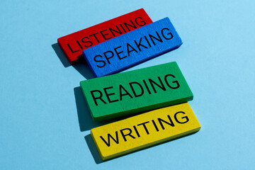 Wooden blocks with text LISTENING, SPEAKING, READING, and WRITING. Four language domains, literacy concept.