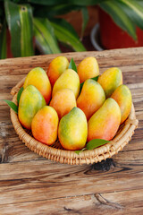 Fresh Ripe Hainan Mangoes in Wicker Basket on Wooden Table - Tropical Fruit Harvest