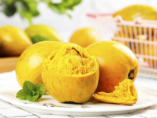 Hainan Golden Egg Yolk Fruit Cut Open Showing Yellow Flesh with Mint Garnish on White Plate