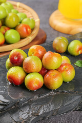 Fresh Red and Green Plums with Water Droplets on Slate Stone Surface